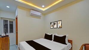 Ein Schlafzimmer mit einem Bett, einer Klimaanlage, einer Holzkommode und einem Fenster mit Jalousien.