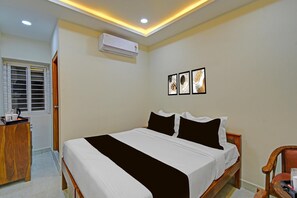 Ein Schlafzimmer mit einem Bett, einer Klimaanlage, einer Holzkommode und einem Fenster mit Jalousien.