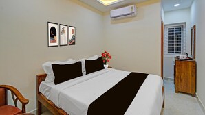Ein Schlafzimmer mit einem Bett, einem Holzstuhl, einer Kommode und Wandbildern.