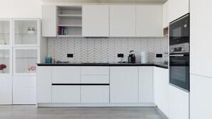 Eine moderne Küche mit weißen Schränken, einer Fischgrätmuster-Fliesenrückwand und einem eingebauten Backofen.