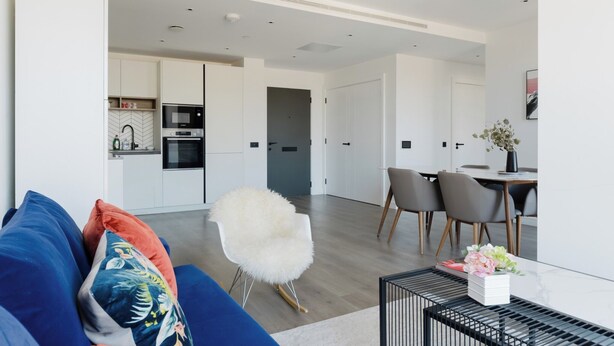 Ein modernes Wohnzimmer mit einer Couch, einem gemütlichen Sessel und einem Essbereich mit Stühlen und einem Tisch.