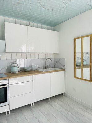 Eine moderne Küche mit weißen Schränken, einer Holz Arbeitsplatte, einer Marmor Spritzwand und einem eingebauten Backofen.