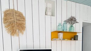 A modern living room with a mounted TV, white furniture, a wicker hanging light, and decorative items on shelves. - A "nice" house (Le Château-d'Oléron)