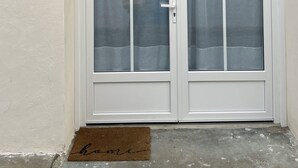 A white double door with a number '3' on the wall, a doormat, and a metal gutter above. - A "nice" house (Le Château-d'Oléron)
