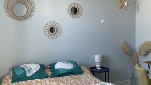 A bedroom with a bed, decorative wall mirrors, a hanging light fixture, and a bedside table with a lamp. - A "nice" house (Le Château-d'Oléron)