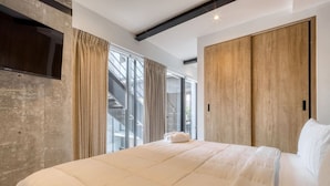 Ein modernes Schlafzimmer mit einem großen Bett, einem an einer strukturierten Wand montierten Fernseher und einem Holzschrank.