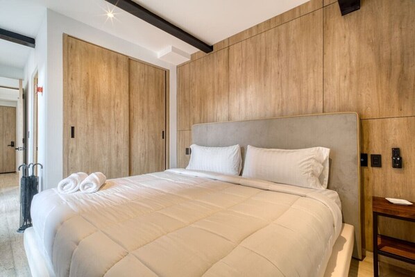 Ein modernes Hotelzimmer mit einem großen Bett, Holzwandverkleidung und minimalistischem Design.