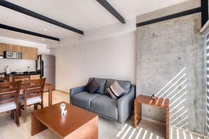 Ein modernes Wohnzimmer mit grauem Sofa, Couchtisch und einem kleinen Beistelltisch.