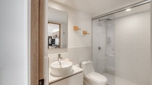 Ein modernes Badezimmer mit Duschkabine aus Glas, einem Waschbecken mit Spiegel und einer Toilette.