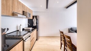 Eine moderne Küche mit Holzausstattung, einem Gasherd, einer Mikrowelle und einem Kühlschrank.