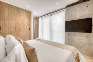 Ein modernes Hotelzimmer mit einem großen Bett, einer Wand aus Holzpaneelen, großen Fenstern und einem fest installierten Fernseher.
