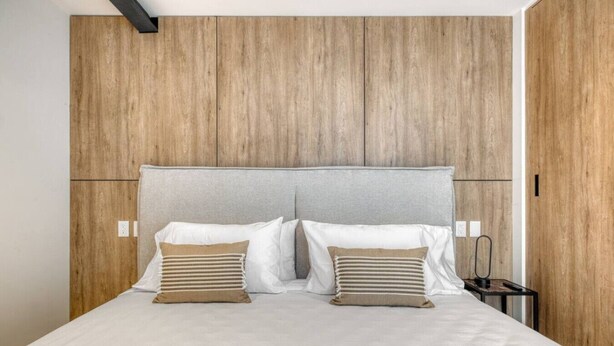 A bed with a grey headboard, two white pillows, and two beige pillows. - Myla 05C - 2BR in Roma Norte - LowF (Mexico City)