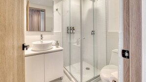 A modern bathroom with a glass-enclosed shower, a white sink, and a toilet. - Myla 05C - 2BR in Roma Norte - LowF (Mexico City)