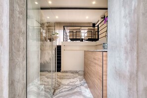 Un interior moderno con un separador de vidrio, suelo de mármol, un mostrador de recepción de madera y una escalera.