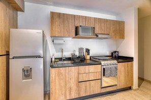 Eine moderne Küche mit Holzschränken, einem Edelstahlkühlschrank, einer Mikrowelle, einem Herd und einem Spülbecken.