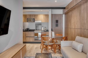 A modern living space with a dining area, kitchen, and a TV mounted on the wall. - Casa Myla - 1BR in Roma Norte - HighF (Mexico City)