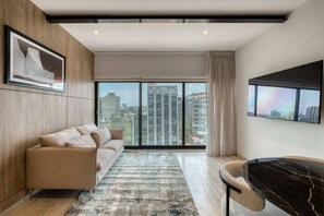 Ein modernes Wohnzimmer mit einer Couch, einem Esstisch und einem großen Fenster mit Blick auf die Stadt.