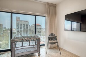 Eine moderne Wohnung mit großem Fenster, einem Bett, einem Sessel und einem an der Wand befestigten Fernseher.