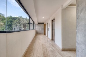 Ein moderner Flur mit einem großen Fenster, einer Betonwand und einem Holzboden.