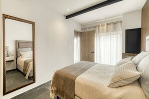A bedroom with a large bed, a mirror, a wardrobe, and a television. - Myla-02C- 1BR Roma Norte - LowF (Mexico City)