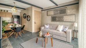 En moderne stue med sofa, sofabord og spiseområde med stole og bord.