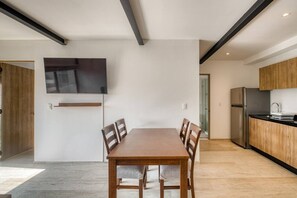 A modern kitchen with a built-in oven, a refrigerator, and a wooden dining table with chairs. - Myla - Casa Calderon - Roma Norte (HF) (Mexico City)
