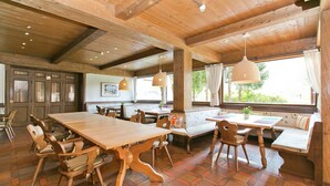 Interior de madera con una gran mesa de comedor, sillas y un banco con cojines.