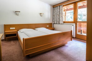 Ein Schlafzimmer mit einem hölzernen Bett, zwei Nachttischen, einem Heizkörper und einem Fenster mit Vorhängen.