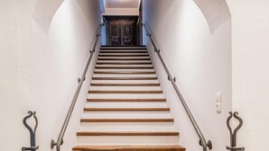 Una escalera de madera con barandillas metálicas que conduce a una puerta de madera oscura al final.