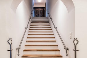 Eine Treppe mit Holzdielen und Metallgeländern, die zu einer dunklen Holztür führt.