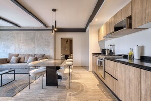 Eine moderne Küche mit Kochinsel, Holzschränken und einer Essecke mit Sofa und Stühlen.