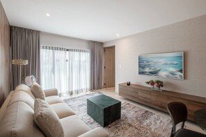A modern living room with a sofa, a coffee table, a TV, and a large window with curtains. - Casa Monroy - 1BR en Roma Norte - LowF (Mexico City)