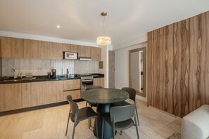 A modern kitchen with wooden cabinets, a round dining table, and a pendant light. - Casa Monroy - 1BR en Roma Norte - LowF (Mexico City)