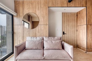 A modern living room with a sofa, a circular mirror, and wooden paneling. - Myla 01 - 1BR - In Roma Norte H (Mexico City)