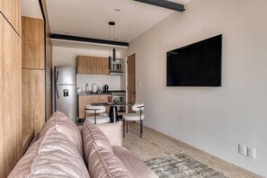 A modern kitchen with a refrigerator, stove, and dining area. - Myla 01 - 1BR - In Roma Norte H (Mexico City)
