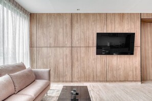 Ein modernes Wohnzimmer mit einer Couch, einem Couchtisch und einem an der Wand montierten Fernseher.