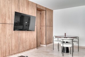 Eine moderne Küche mit Holzausstattung, einem integrierten Fernseher und einem runden Esstisch mit Stühlen.