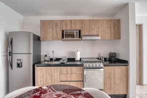 A modern kitchen with a refrigerator, stove, oven, and wooden cabinets. - Myla 04C - 1BR In Roma Norte - HighF (Mexico City)