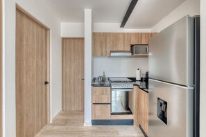 A modern kitchen with wooden cabinets, a stainless steel refrigerator, and a built-in oven. - Superior 2 BR near Reforma (Mexico City)
