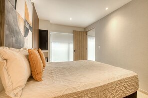 A bedroom with a bed, pillows, a door, and a wall with a painting. - Myla - 01C Roma Norte - LowF (Mexico City)