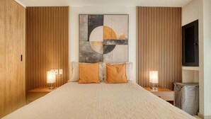 A hotel room with a large bed, wooden paneling on the walls, a large abstract painting, two bedside lamps, and a television on the wall. - Myla - 01C Roma Norte - LowF (Mexico City)