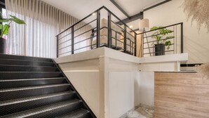 A staircase with a textured black finish, a white wall, and a wooden panel on the right. - Myla - 01C Roma Norte - LowF (Mexico City)