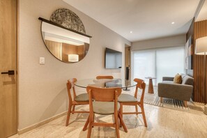 A modern hotel room with a dining area, a sofa, a TV, and a large mirror. - Myla - 01C Roma Norte - LowF (Mexico City)