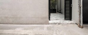 Ein Gebäude mit einer Betonfassade, einer Metalttür und einem gefliesten Eingangsbereich.