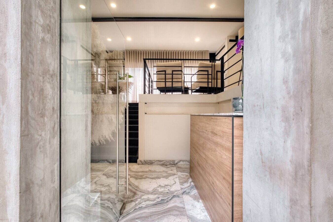 A modern interior with a glass wall, a staircase, and a wooden counter.