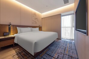 A hotel room with a large bed, bedside table, and a wall-mounted artwork. - UrCove by Hyatt Nanjing South Railway Station BaiJia Lake (Nanjing)
