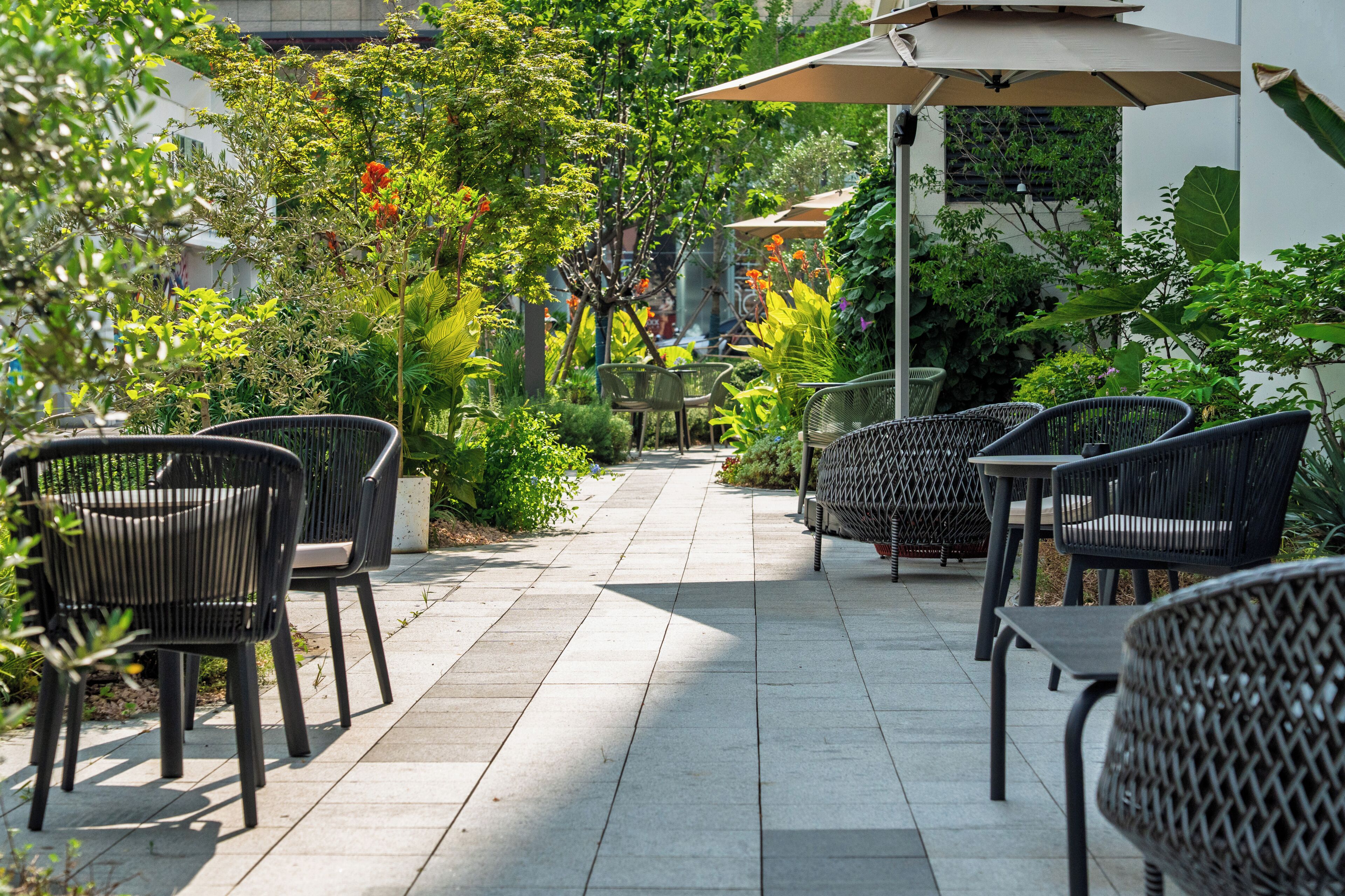 Un patio al aire libre con mobiliario de mimbre y piso de baldosas.