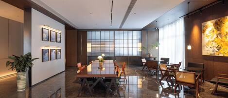 Una sala de conferencias moderna con piso de mármol pulido, una mesa larga con sillas y un amplio ventanal con vistas.