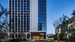 Un hotel di grandi dimensioni dal design moderno, caratterizzato da una struttura verticale imponente e un ingresso ben illuminato.