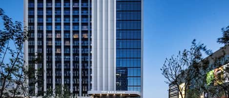 A high-rise hotel with a modern design, featuring a prominent vertical structure and a well-lit entrance.